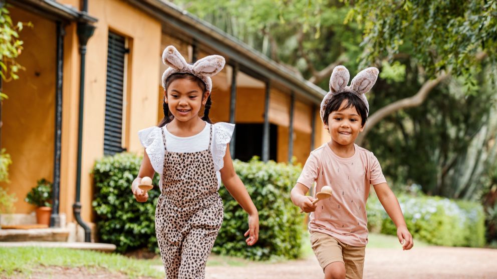 Two children wearing fluffy bunny ears playing egg and spoon race at Elizabeth Farm, parramatta