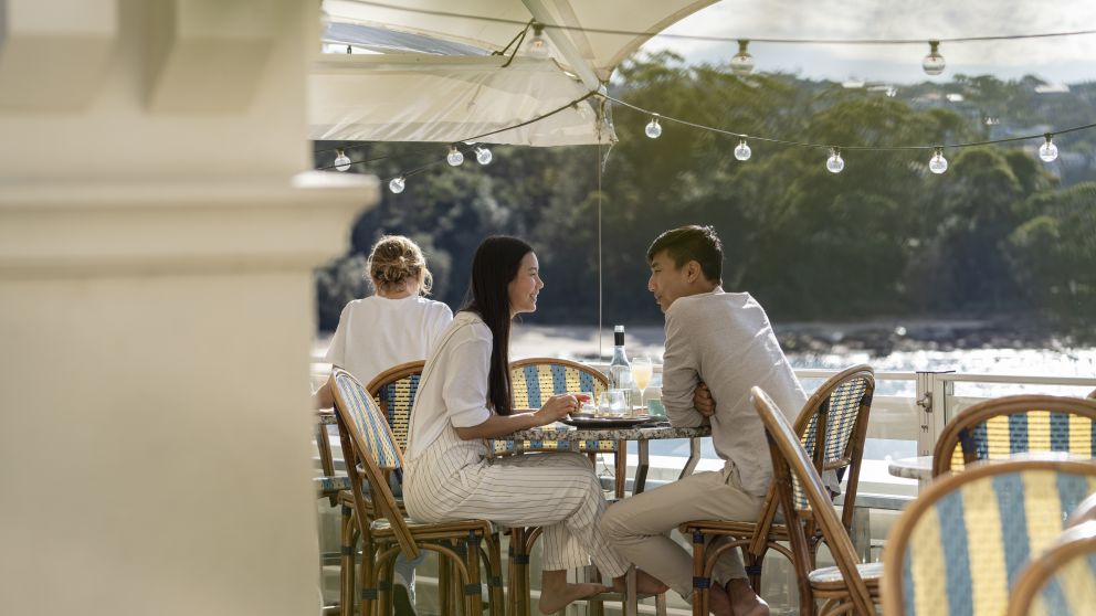 Couple enjoying food and drink with views of Balmoral Beach at Bathers Pavilion, Mosman