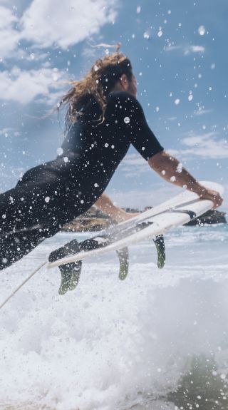 Surfer heading out to catch a wave at Bronte Beach, Sydney