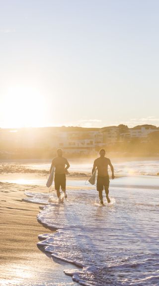 Surfers heading for a morning surf at Bondi Beach