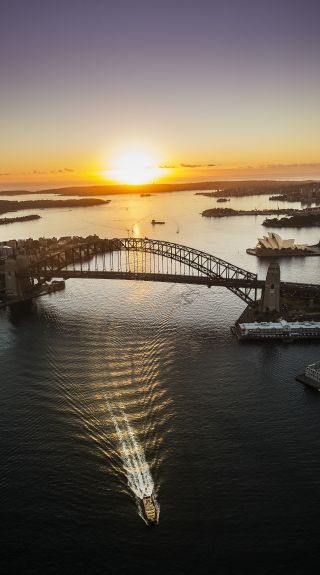 Aerial of the sun rising over Sydney Harbour with views of the Sydney Harbour Bridge