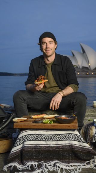 Hayden Quinn cooking Lemongrass Pork Roll with Opera House in background, Sydney Harbour