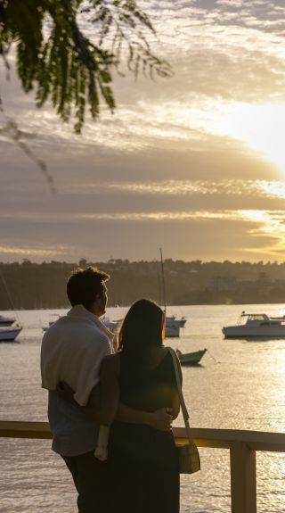 Couple watching the sun setting over North Harbour, Manly
