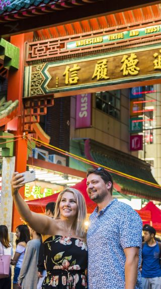 Couple take a selfie in front of the Chinatown gates on Dixon Street, Sydney City