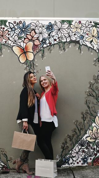 Friends taking a selfie in front of Aaron Favaloro street art, Paddington