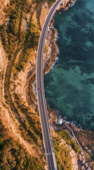 Aerial overlooking cars driving along Sea Cliff Bridge in Clifton, Illawarra