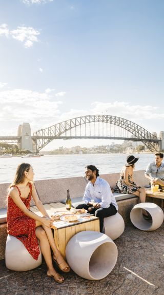 Couple enjoying food and drink with harbour views at Opera Bar, Sydney.