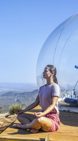 Woman relaxing by her Bubbletent Australia accommodation in the Capertee Valley