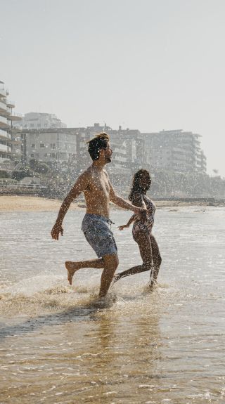 Couple running into the surf at South Cronulla Beach, Cronulla