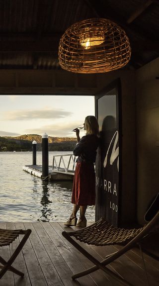 Woman enjoying a beverage with scenic views across Hawkesbury River at Marramarra Lodge, Berowra Waters