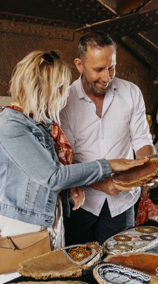 Couple browsing through Aboriginal artwork for sale at the Blak Markets on Bare Island, La Perouse