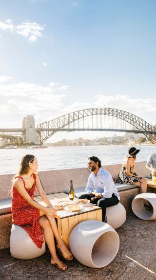 Couple enjoying food and drink with harbour views, Opera Bar, Sydney