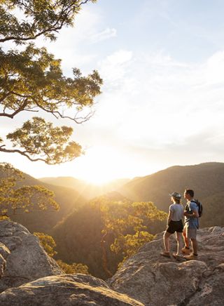 Couple watching a scenic sunset over the Hawkesbury Valley from the Vale of Avoca lookout in Grose Vale