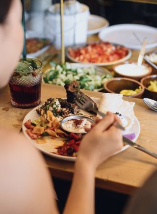Woman enjoying food and drink at Cairo Takeaway on Enmore Road, Newtown in Sydney's inner west
