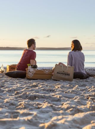Couple enjoying a picnic packed by Hyams Beach Hampers at Blenheim Beach, Jervis Bay