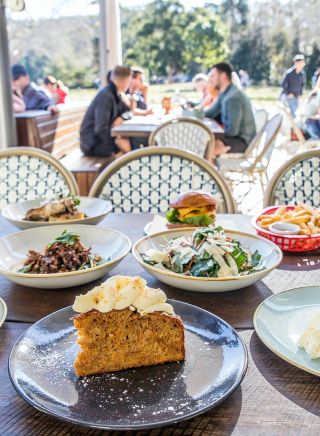 Assortment of foods on timber table overlooking parkland at Audley Dance Hall Cafe and Events, Royal National Park