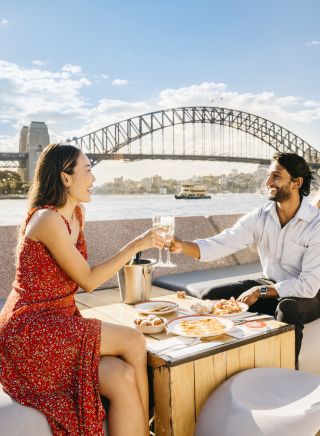 Couple enjoying drinks at sunset by Sydney Harbour