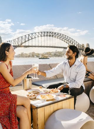 Couple enjoying drinks at sunset by Sydney Harbour