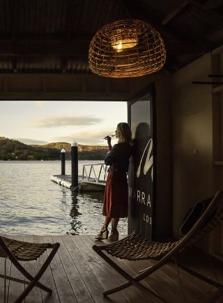 Woman enjoying a beverage with scenic views across Hawkesbury River at Marramarra Lodge, Berowra Waters