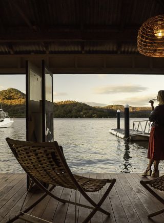 Woman enjoying a beverage with scenic views across Hawkesbury River at Marramarra Lodge, Berowra Waters