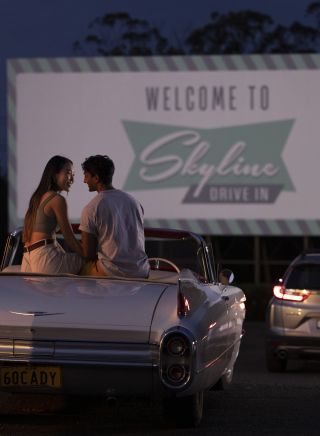ブラックタウンのスカイライン・ドライブインで、映画を見る準備をしながら車に座っているカップル。