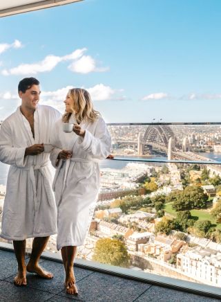 Couple enjoying a coffee and harbour views from their luxurious Crown Towers hotel suite at Crown Sydney, Barangaroo