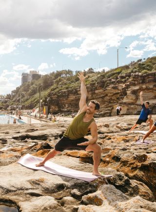 Group enjoying a yoga session by the ocean, Freshwater Beach