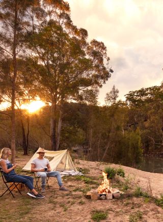 Couple enjoying a campfire by their tent on the Hawkesbury River, Lower MacDonald