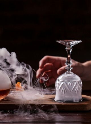  A smoking bottle on a wooden board with a hand about to turn over a smoke filled glass - Sydney - Credit Eau De VieATDW - Smokey Rob - Roy Eau De Vie - A smoking bottle on a wooden board with a hand about to turn over a smoke filled glass, Sydney - Credit: Eau De Vie