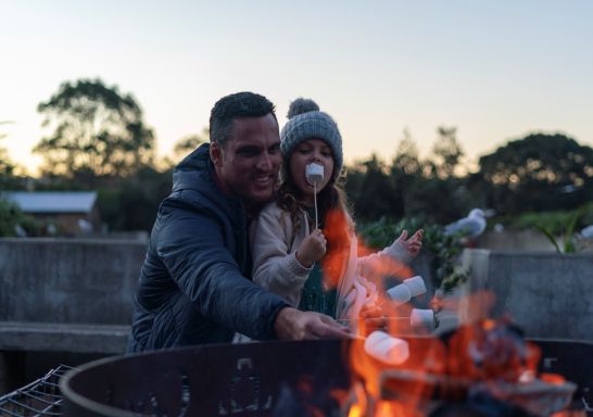 Family relaxing and roasting marshmallows at their waterfront campsite, Cockatoo Island, Sydney Harbour