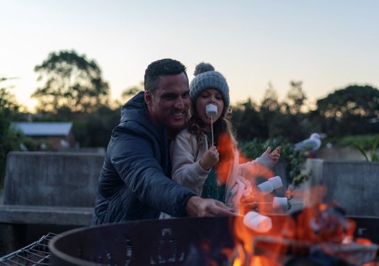 Family relaxing and roasting marshmallows at their Cockatoo Island waterfront campsite