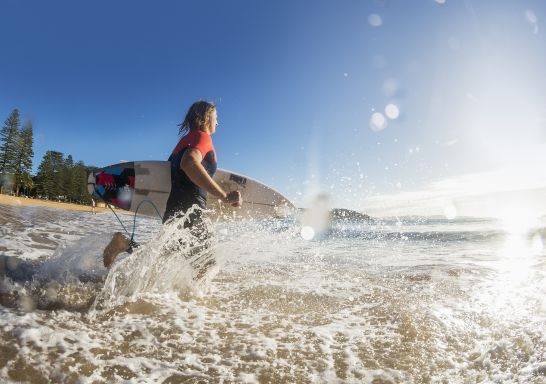 Man heading out to enjoy a morning surf at Sydney's Palm Beach